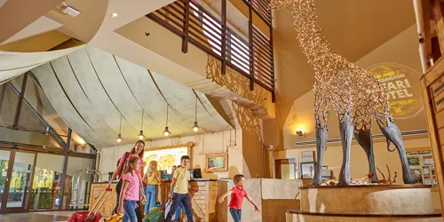 Families walking though the lobby of the Chessington Safari Hotel with giraffe statue