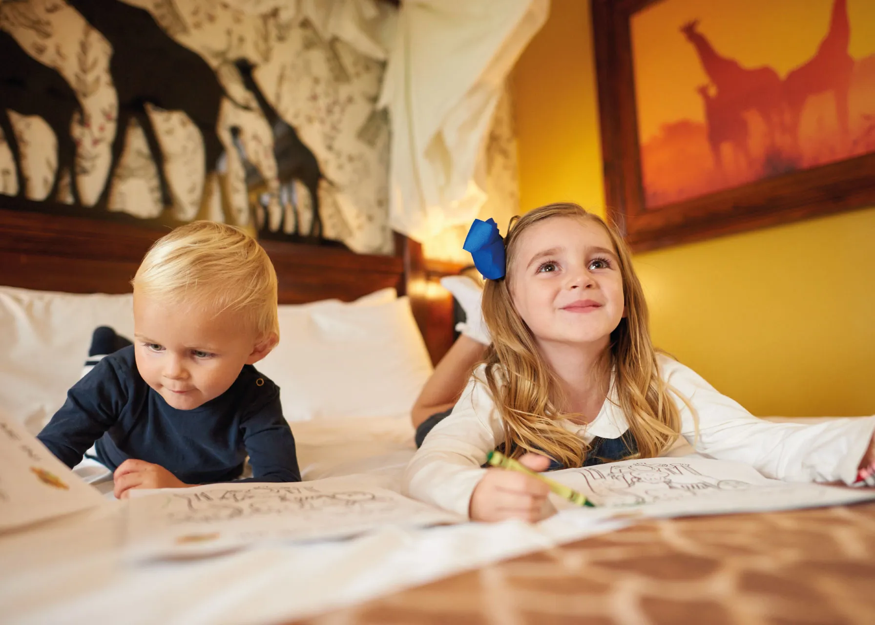 Children colouring on bed in a Giraffe themed room in the Chessington Safari Hotel