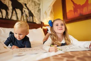 Children colouring on bed in a Giraffe themed room in the Chessington Safari Hotel